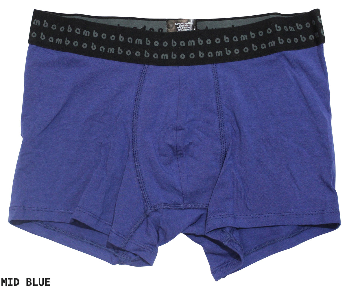 These men's Bamboo Trunks in mid-blue are designed for optimal comfort and feature anti-bacterial properties. The black waistband is adorned with "bambo" repeatedly printed in light blue, while the soft and stretchy fabric ensures a perfect fit. "MID BLUE" is subtly written in black on the bottom left corner.
