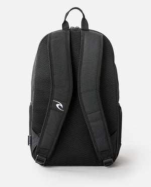The Rip Curl Ozone 30L School Eco Backpack, made from recycled plastic, is displayed from the back. It includes two padded shoulder straps with a logo on the right one, a grey mesh back panel for ventilation, and a top handle. A laptop compartment is inside. The background is plain white.