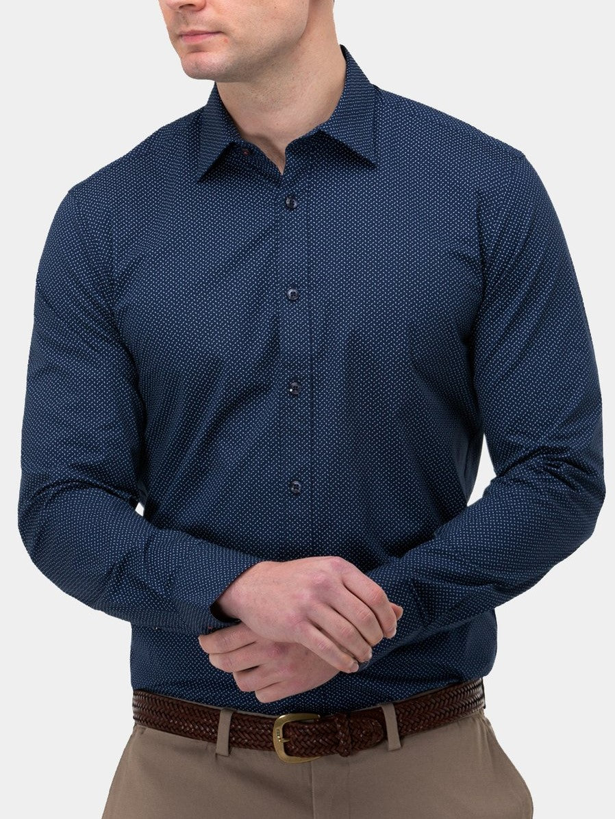 A person wears a comfortable dark blue Brooksfield Stretch Print Shirt with light brown trousers, arms crossed, displaying a braided brown belt against a plain white backdrop.