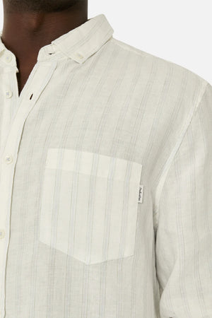Close-up of a person wearing the Industrie The Bilbao Long Sleeve Shirt, showcasing its button-down collar and front pocket with a small label. This light linen shirt features thin vertical stripes and a relaxed fit, with visible button details between mid-chest and neck.