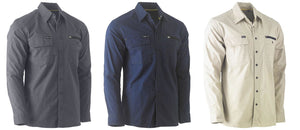 Three long-sleeve Bisley Flex & Move Utility Work Shirts are displayed. From left to right, the colors are dark gray, navy blue, and beige. Each shirt features two chest pockets with buttoned flaps, a small logo tag, and offers SPF 50+ protection.