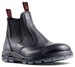 The Redback UBBK Bobcat Soft Toe is a black leather work boot with elastic sides and distinctive red pull tabs on the front and back. This handmade Australian boot features a soft toe, a black sole with a clear, textured bottom, and visible stitching along its body.