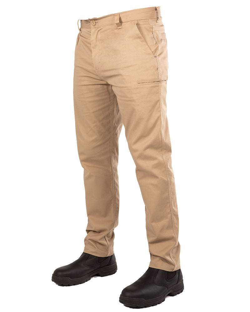A person wearing UNIT Ignition Stretch Pants in beige, crafted from durable work pant stretch fabric, alongside black work boots. The pants, designed for functionality, feature side pockets and a zipper pocket on the right thigh. The image is focused on the legs, with the upper body not visible.