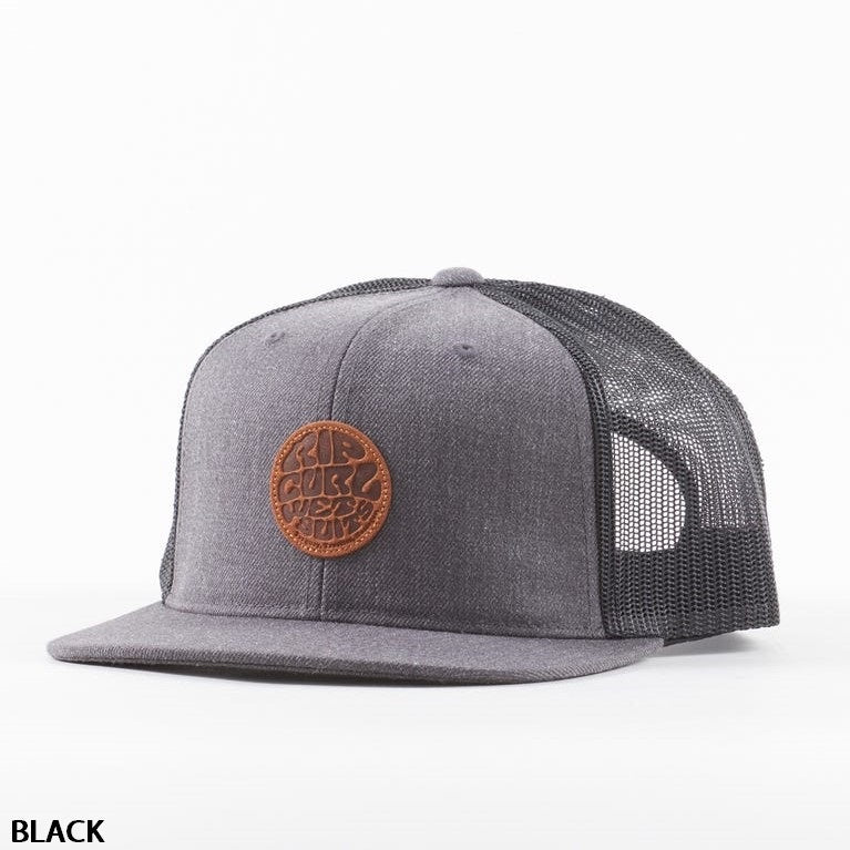 A black mesh baseball cap with a solid fabric front panel featuring a round brown leather patch displaying an embossed design. The Rip Curl Premium Wetty Trucker has a flat brim, adjustable strap, and a button on top. The background is plain white, with "BLACK" printed in the bottom left corner.