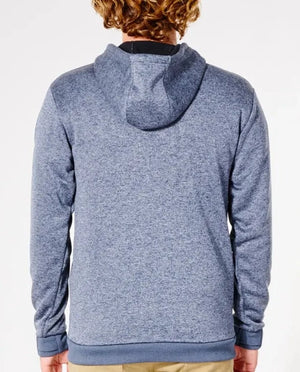 A person with curly hair is seen from behind, wearing a blue Rip Curl Anti Series Crescent Hood and beige pants. The hoodie has long sleeves and a Durable Water Resistant hood for protection against the elements. The background is white.