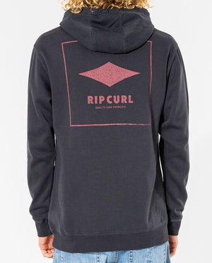 The rear view shows someone in a dark cotton/polyester hoodie with a pink Rip Curl logo and "Rip Curl Quality Products Hood" text on the back. Their curly hair complements the casual look, paired with classic blue jeans.