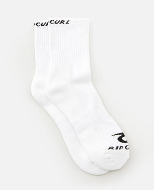 Two white socks from the Rip Curl Corp Crew Sock 5 Pack, size Men's 9-13, are displayed on a plain white background. "Rip Curl" is written in black on the top of the cuff and by the toes of each sock. The socks are placed side by side, slightly overlapping each other.