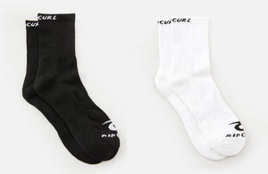 Two pairs of socks from the Rip Curl Corp Crew Sock 5 Pack are displayed side by side. The left pair is black, and the right pair is white. Each sock, designed for men's sizes 9-13, features the brand name written at the top and on the toes in contrasting colors to the sock itself. The background is plain white.