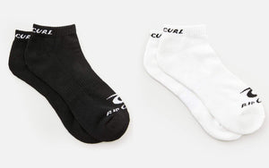 Two pairs of socks from the Rip Curl Corp Ankle Sock 5 Pack are displayed side by side on a light background. The pair on the left is black with "RIP CURL" written in white at the top and on the toe. The pair on the right is white with "RIP CURL" written in black, both featuring arch support for added comfort.