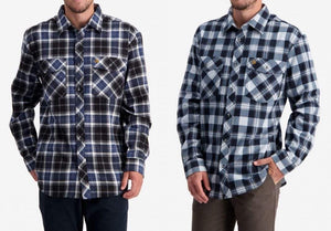 Two men are shown wearing shirts from the Swanndri Egmont Full Button Flannelette Twin Pack. The man on the left sports a black, white, and blue plaid shirt paired with dark pants, while the man on the right wears a light blue and white plaid shirt with brown pants. Both shirts feature two chest pockets and are made of 100% brushed cotton.