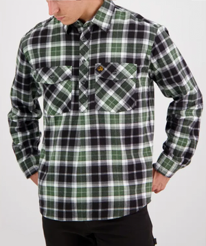 A person is wearing a checkered Swanndri Egmont Flannelette shirt in green, black, and white with two chest pockets. Made from 100% brushed cotton to ensure comfort and style, the person stands against a plain light background, looking down.