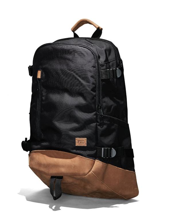 The FXD WBP-3 Work Backpack combines functionality and style with a durable leather base, multiple zippers and straps, Cordura Ballistic Fabric construction, a top carrying handle, and a convenient side pocket. It stands upright against a light background.