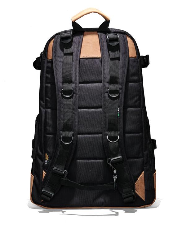 The FXD WBP-3 Work Backpack, in black with brown accents, is shown from the back with padded shoulder straps and multiple adjustment buckles. Made from durable Cordura Ballistic Fabric, it has a sturdy top handle, leather base for resilience, and a quilted back panel for comfort.