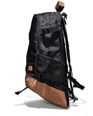 Side view of the FXD WBP-3 Work Backpack, showcasing its sleek black and brown design. Made from durable Cordura Ballistic Fabric, it has a zipped main compartment and adjustable straps. A leather patch with a logo adorns the side, complemented by brown accents on the leather base.
