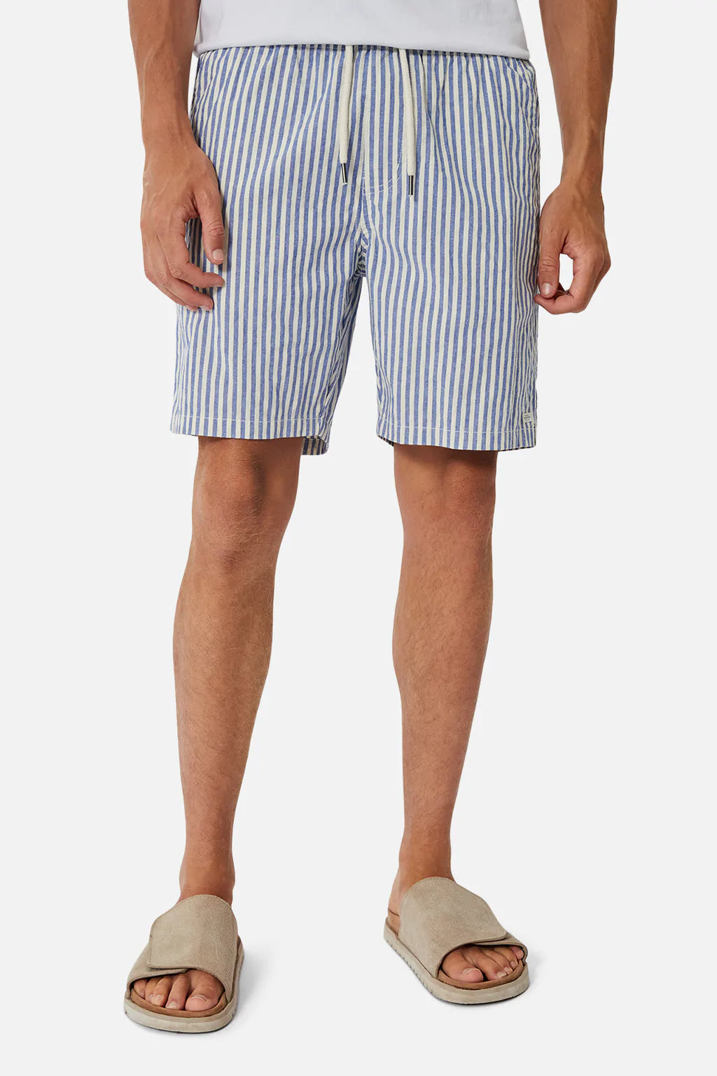 Someone wearing Industrie The Laguna Short, featuring stylish blue and white stripes with a drawstring and elastic waist, paired with beige sandals. The background is plain white.