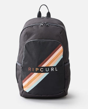 The Rip Curl Ozone 30L Multi Backpack in black showcases a striking rainbow stripe design diagonally across the front pocket, with the "Rip Curl" brand name printed over the stripes. It features multiple zipper compartments, a dedicated laptop section, and a top handle for easy carrying.