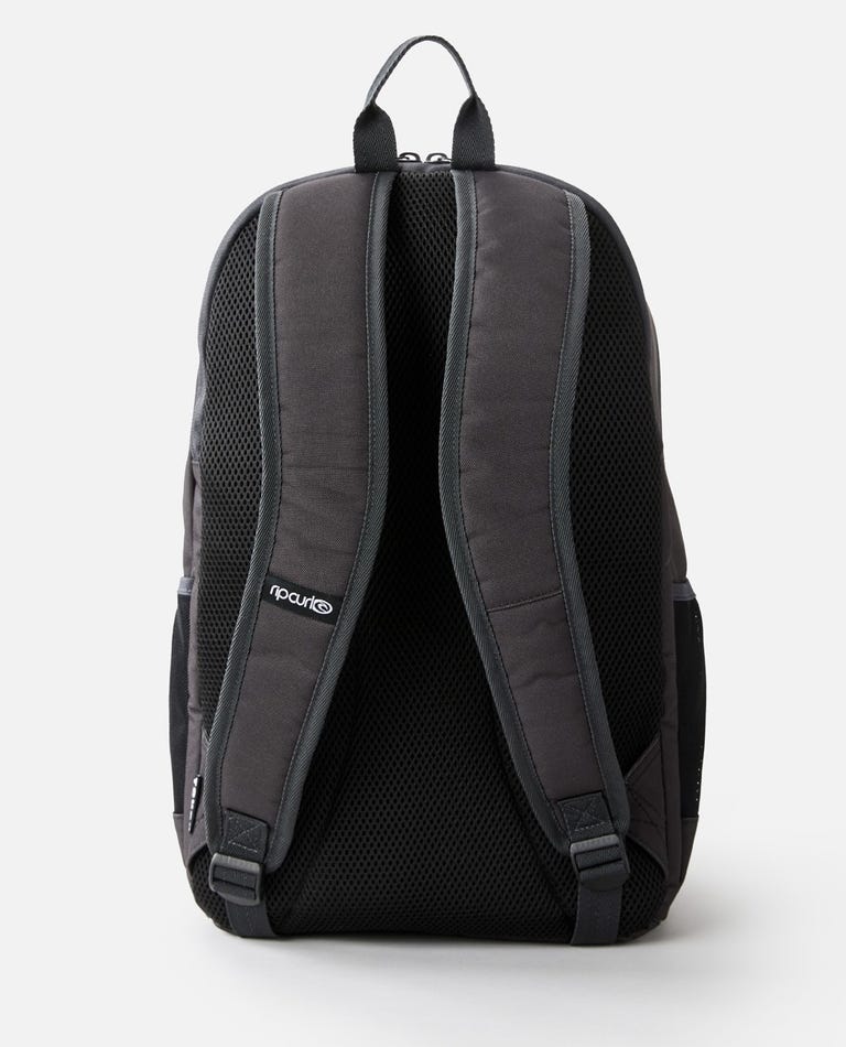 The Rip Curl Ozone 30L Multi Backpack in black is shown from the back, highlighting its padded shoulder straps and top carrying handle. The brand's logo is clearly visible on the left shoulder strap. Constructed from durable material with mesh padding for added comfort, it also includes a dedicated laptop section to keep your device secure.