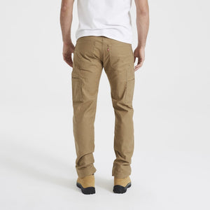 A person wearing a white t-shirt, khaki Levis Workwear 505 Utility Pants, and tan boots is standing with their back facing the camera. The image highlights the durable pockets of the work pants, showcasing multiple sturdy compartments.