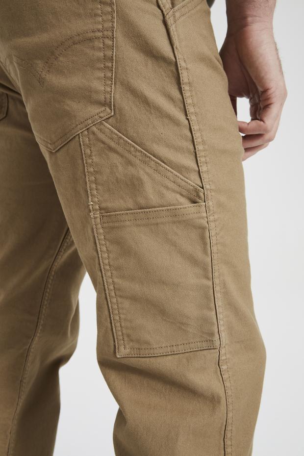 A close-up image of a person wearing Levis Workwear 505 Utility Pant in khaki color. The photo emphasizes the side and back pockets, showcasing the intricate stitching and rugged pockets. The fabric looks robust, and part of the person's hand is visible in the frame.