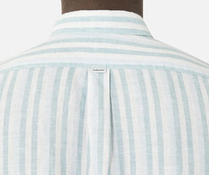 Close-up of the back of a person wearing a light blue and white striped Industrie The Linenman Shirt. The relaxed fit shirt features a small label beneath the button-down collar, with lightweight and breathable fabric.