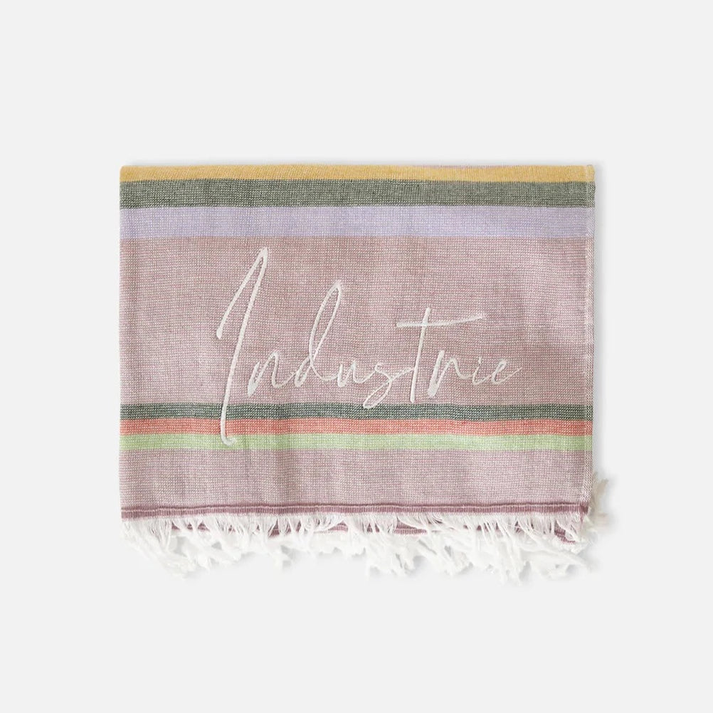 The Industrie The Maurepas Turkish Towel features a multicolored design with horizontal stripes in pink, yellow, green, and purple hues and "Industrie" written in white script across the center. Made of soft cotton, it is finished with elegant white fringes at the bottom edge.