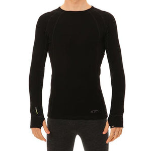 A person wearing the XTM Merino Long Sleeve Top, a fitted, long-sleeved thermal top in black with a round neckline and odour repellent properties, along with dark-colored pants is shown against a white background. The person has their arms relaxed by their sides, and the image primarily highlights the clothing.