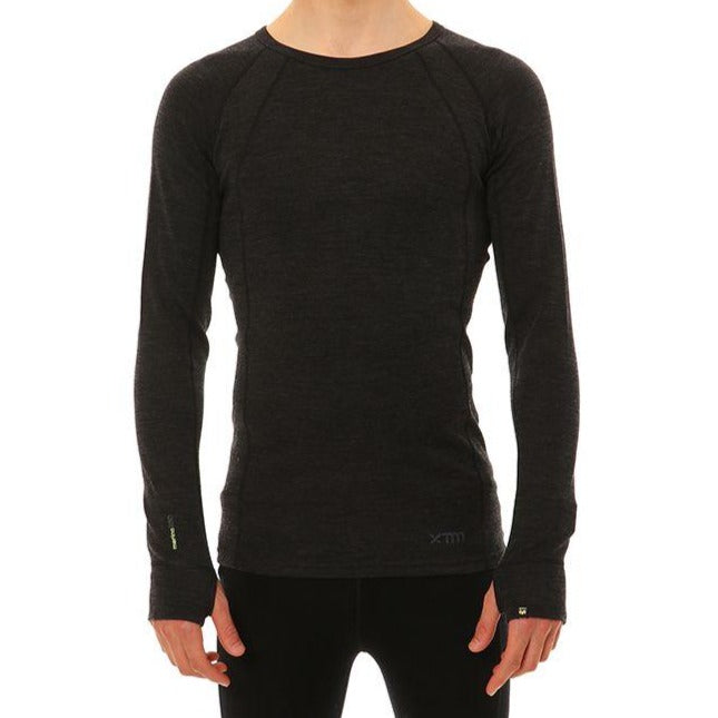 A person is wearing an XTM Merino Long Sleeve Top, a fitted, black thermal top made from Australian Merino Wool. The neckline is round and collarless, providing an odour repellent feature. There are no other visible details or accessories against the plain white background.