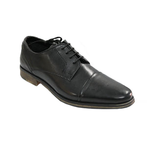 A single black One4TheRoad Harrison Shoe with a lace-up design, featuring a polished leather finish and a low wooden heel. The shoe is positioned at an angle, showing the side and front view, complemented by a synthetic lining for added comfort.
