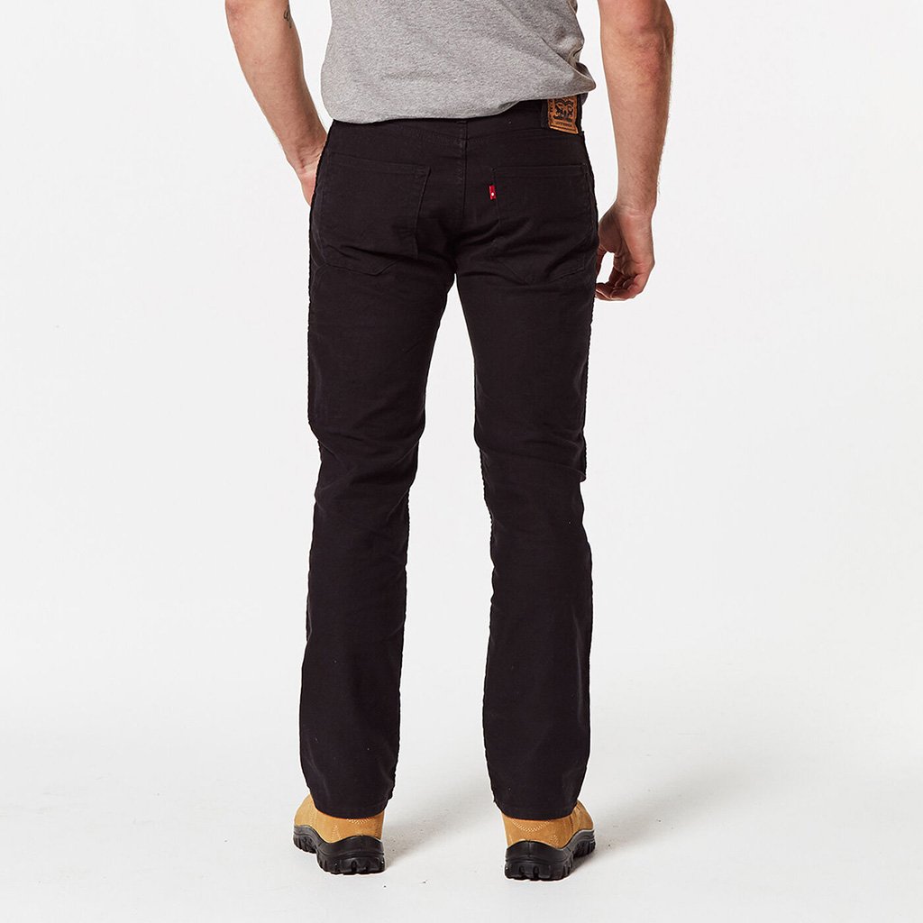 A person is shown from the back wearing slim fit black pants and a grey shirt, paired with beige and black shoes. The image prominently displays the full length of the Levis Workwear 511 Utility Slim Jean as they stand against a plain white background.