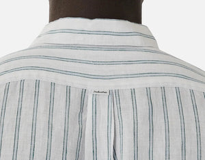 A person is seen from behind wearing the Industrie The Paglia Long Sleeve Shirt, a relaxed fit made of 100% linen. It features thin vertical green stripes, a straight collar, back yoke, and an embroidered tag in the center against a plain white background.