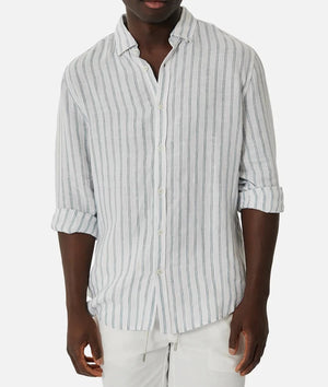 A man in the Industrie The Paglia Long Sleeve Shirt, with rolled-up sleeves and relaxed fit light gray stripes, pairs it with white pants against a plain white background.