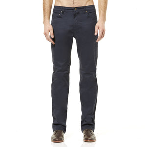 A man standing against a white background, wearing Riders Straight Pant Stretch and brown leather shoes. The image is cropped from the shoulders down.