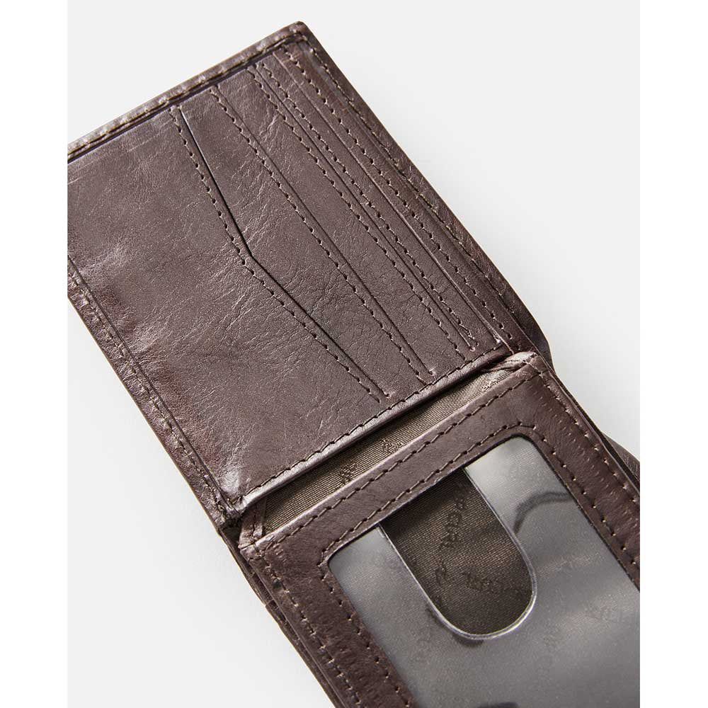A Rip Curl Perforation RFID Slim Wallet in brown leather is open, showing off its card slots and transparent ID holder. Set against a plain white background, the wallet's texture showcases its craftsmanship, merging style with function.