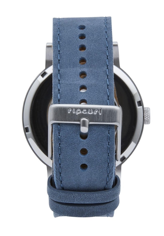 The Rip Curl Circa Leather Watch boasts a blue suede strap with a silver buckle, elegantly engraved with the brand name "Rip Curl." The marine-grade stainless steel watch face is partially visible behind the genuine leather band, which includes multiple adjustment holes for precise sizing.