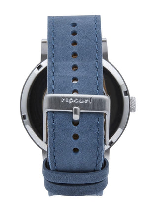 The Rip Curl Circa Leather Watch boasts a blue suede strap with a silver buckle, elegantly engraved with the brand name "Rip Curl." The marine-grade stainless steel watch face is partially visible behind the genuine leather band, which includes multiple adjustment holes for precise sizing.