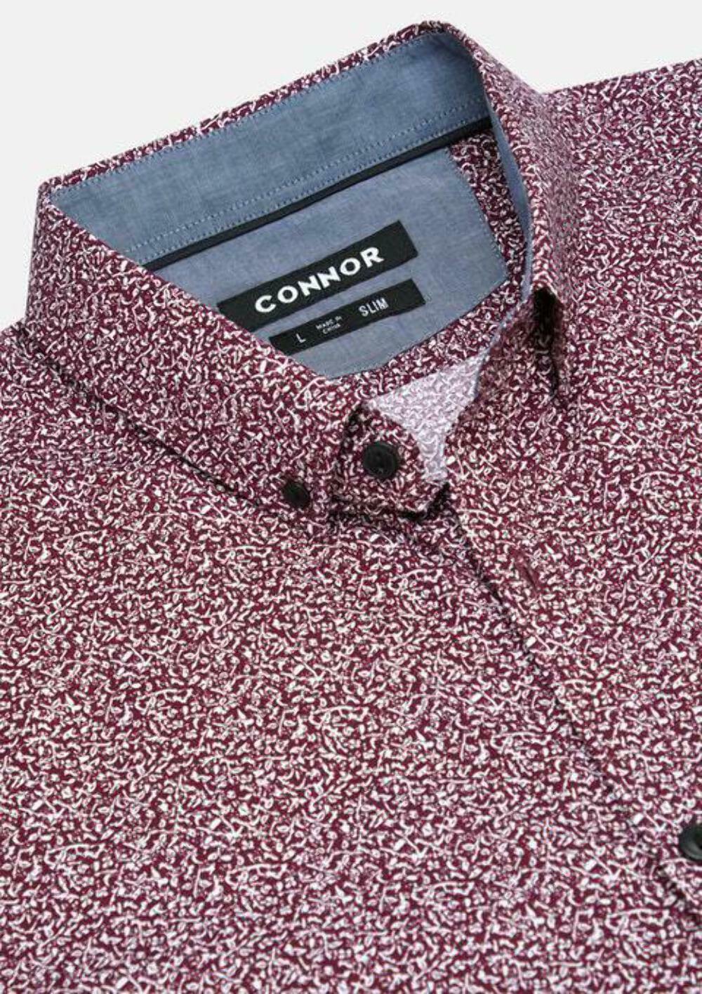 Close-up of the Connor Tate Print Shirt, a maroon and white patterned slim fit made from 100% cotton with a button down collar. The inner label shows "CONNOR" along with size and fit information.