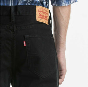 A person wearing black Levi's 516 Straight Jeans with a comfortable fit and a visible brown leather patch on the waistband, and a plaid shirt tucked in. The 100% cotton jeans show the brand's signature red tab and stitching on the back pocket. The person is seen from the back, showing waist to mid-thigh.