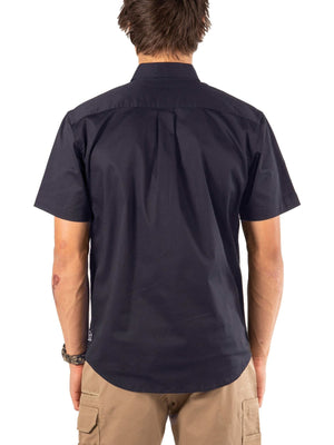 A man wearing the UNIT Craftman Stretch Short Sleeve Shirt in navy and khaki pants stands facing away from the camera against a white background.