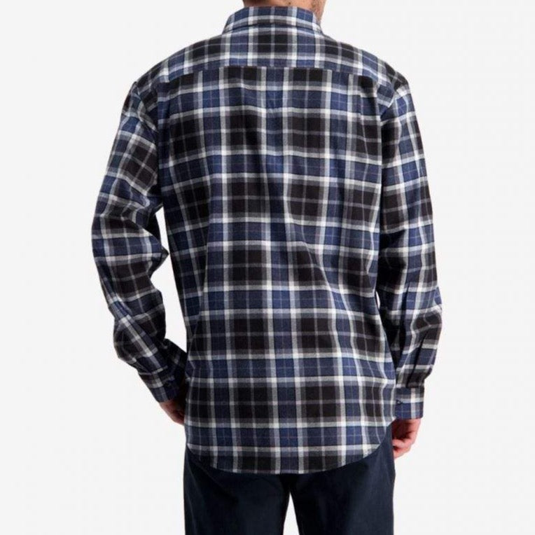 A person stands facing away from the camera, wearing a long-sleeved plaid shirt in blue, white, and black from the Swanndri Egmont Full Button Flannelette Twin Pack collection. The shirt is made from 100% brushed cotton and is paired with dark pants. The background is plain and light-colored, emphasizing the attire.
