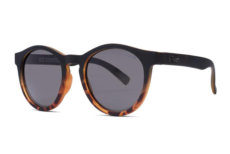 The Liive Six Shooter Sunglasses boast a sleek, modern design with round dark lenses, a tortoiseshell-patterned frame, and lightweight polycarbonate material. These stylish shades provide UV protection and complement various face shapes and occasions.