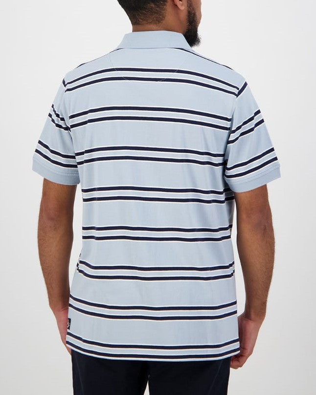 A person with short hair and a beard is seen from the back, wearing a light blue Swanndri Lincoln Stripe Polo featuring horizontal navy and white stripes. Made from 100% cotton, this casual polo shirt stands out against the plain white background.