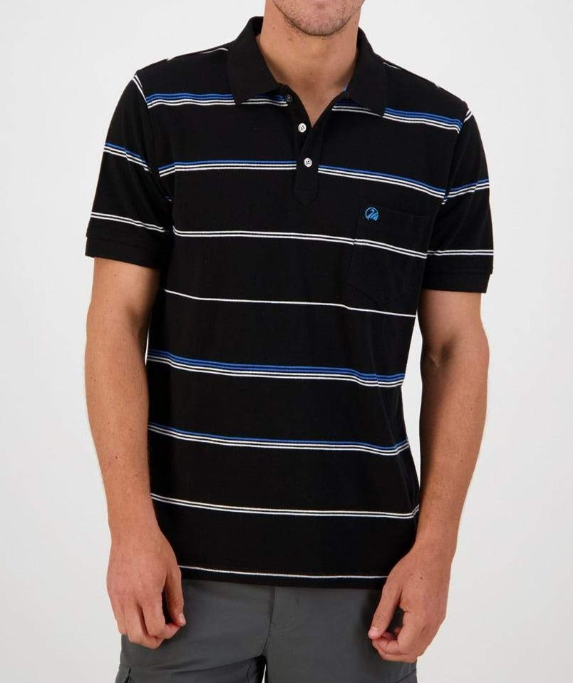 A person is wearing the Swanndri Concord Stripe Polo, a black, short-sleeved, 100% cotton shirt with horizontal stripes in blue and white. They are standing with arms relaxed by their sides. The casual polo features a small pocket on the left side of the chest and is paired with gray pants.