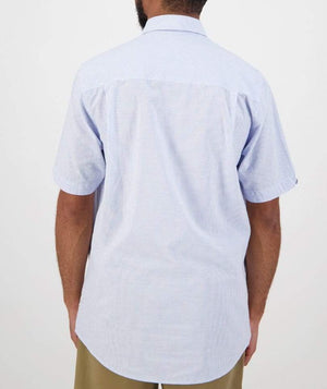 A person in a Swanndri Hinsdale Shirt, light blue and white striped, stands against a white background. This short-sleeve shirt has a classic fit with a classic collar and straight hemline, crafted from 100% cotton for ultimate comfort. They're wearing it with khaki pants.