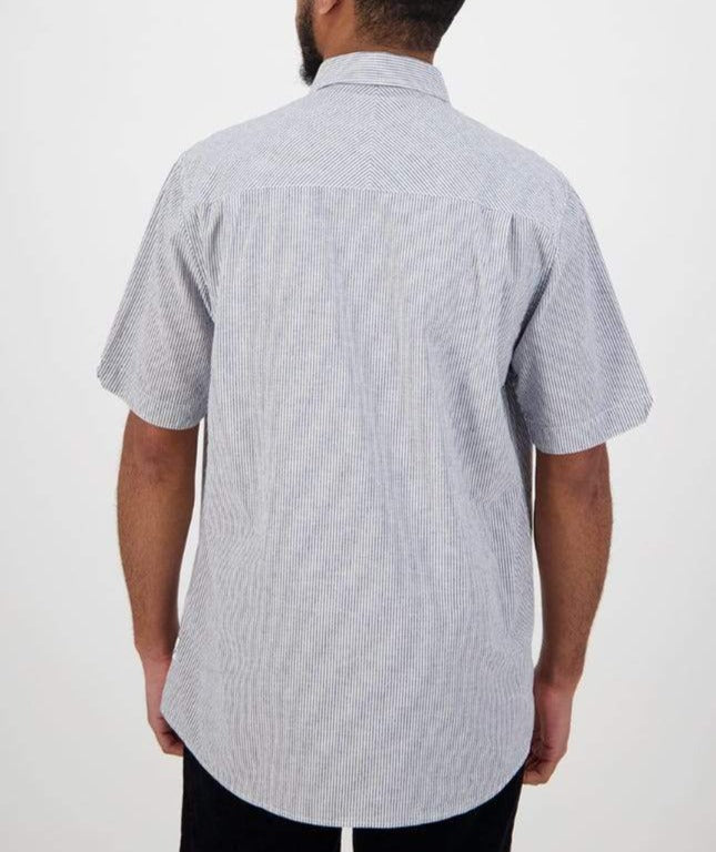 A person with short hair and a beard is wearing the Swanndri Hinsdale Shirt, a comfortable, short-sleeved, light gray button-up with subtle vertical stripes. The classic fit ensures ease as they face away from the camera against a plain background.