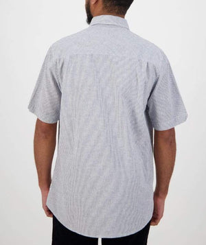 A person with short hair and a beard is wearing the Swanndri Hinsdale Shirt, a comfortable, short-sleeved, light gray button-up with subtle vertical stripes. The classic fit ensures ease as they face away from the camera against a plain background.
