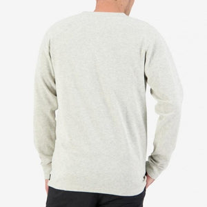 Rear view of a person wearing the Swanndri Oxford Henley, a light gray, long-sleeve casual top with waffle knit detailing, paired with black pants. The person's right hand is placed on their hip while the left arm hangs by their side. The background is plain white.
