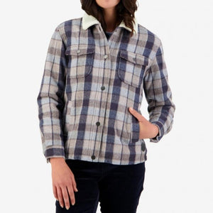 A person wearing the Swanndri Kaituna Womens Sherpa Lined Jacket, featuring a stylish blue and gray plaid pattern with a white sherpa collar, stands against a white background. The person has one hand in their pocket and their head is partially cropped out of the frame.