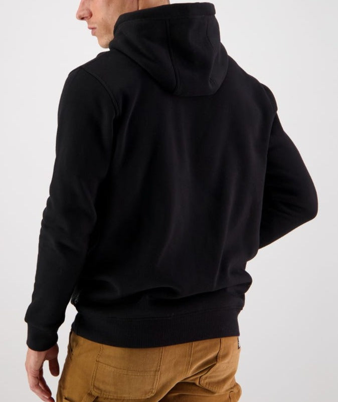 The image depicts someone wearing the Swanndri Original Fleece Hoody paired with brown pants from behind. The hood partially covers their head, and their left hand rests on their hip. The background is light-colored and plain.