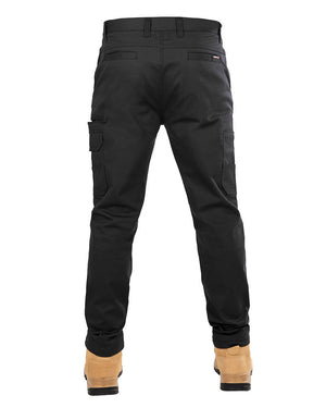 A rear view of a person wearing the UNIT Demolition Stretch Cargo Pant and tan work boots. The black cargo pants feature multiple pockets, including side cargo-style pockets, and belt loops at the waist. The boots are sturdy with reinforced heels and soles.