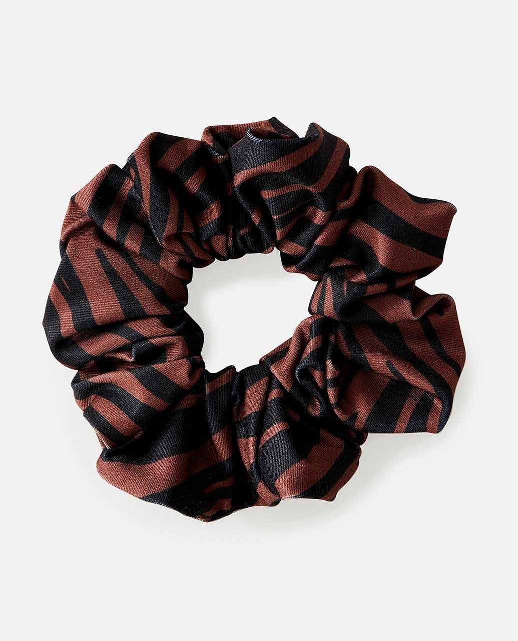 The Rip Curl Sun Tribe Scrunchie features a brown knit fabric with a circular pattern of black abstract stripes on a plain white background.